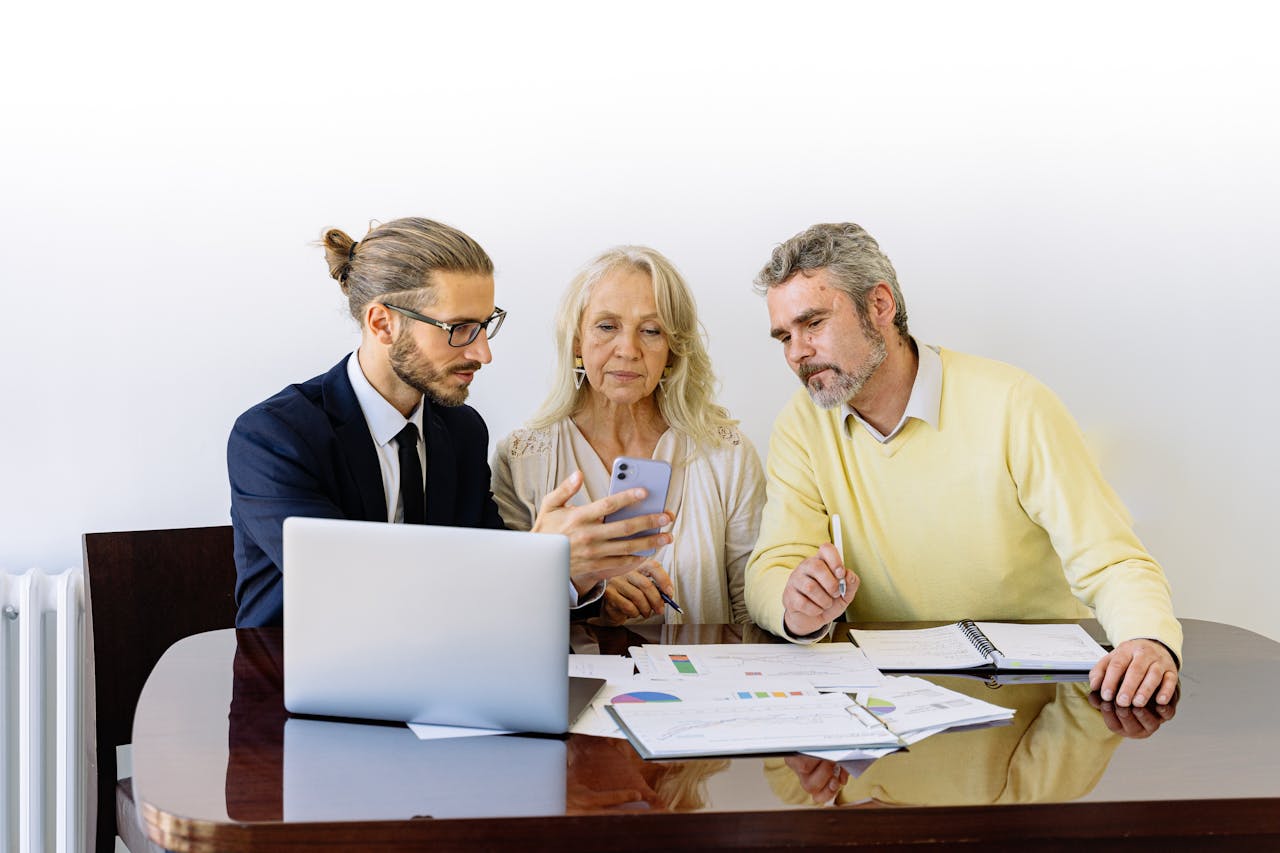 about-04 Three individuals collaborating on financial documents during a business meeting.